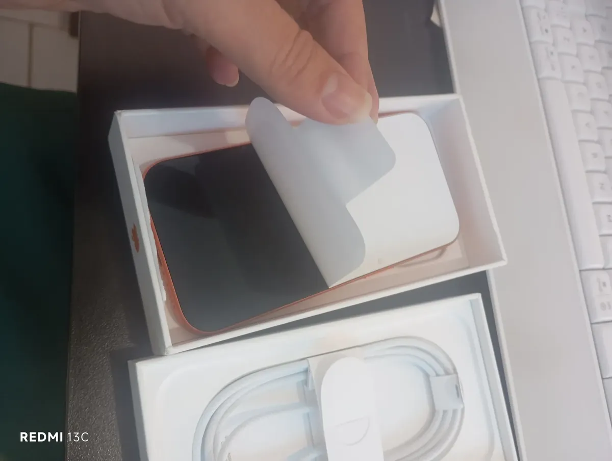 Cliente retirando a proteção do iPhone dentro da caixa