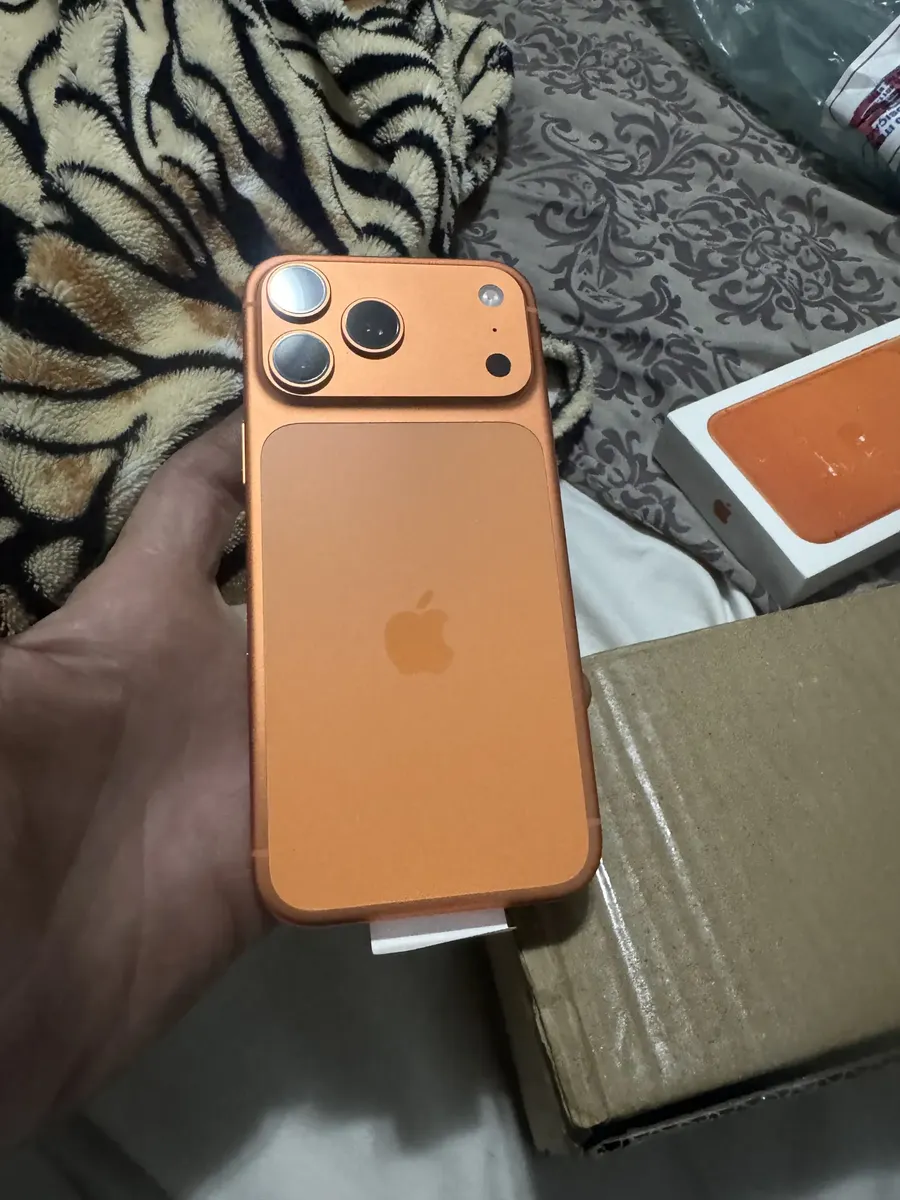 Traseira do iPhone 17 Pro Max laranja na mão do cliente